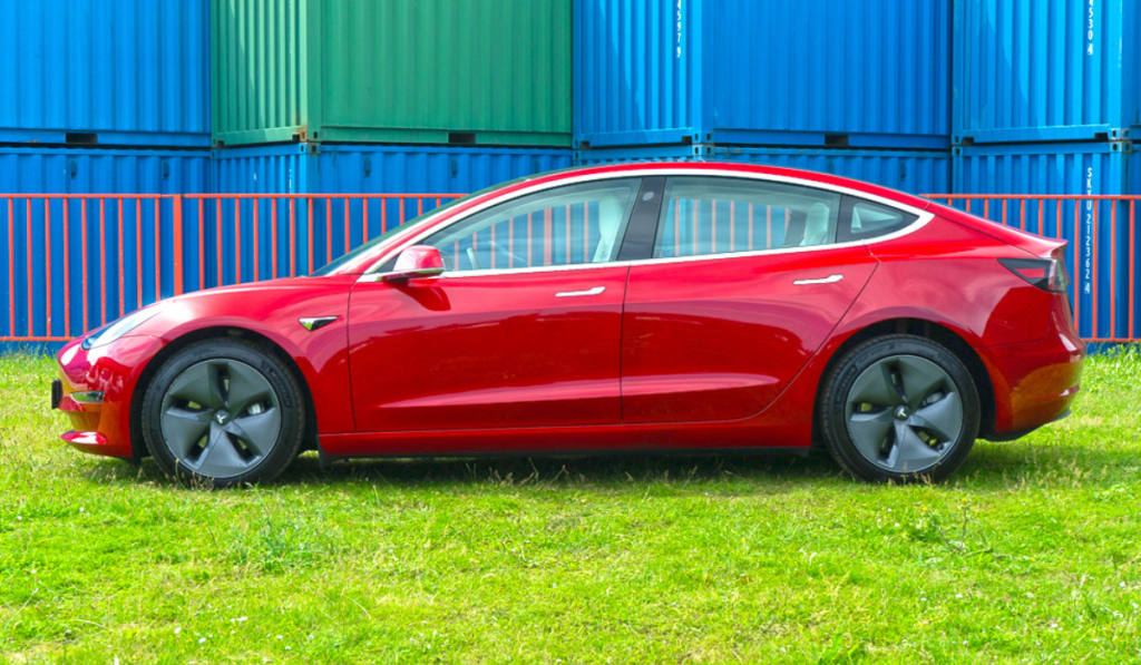 Red tesla model 3 facing left