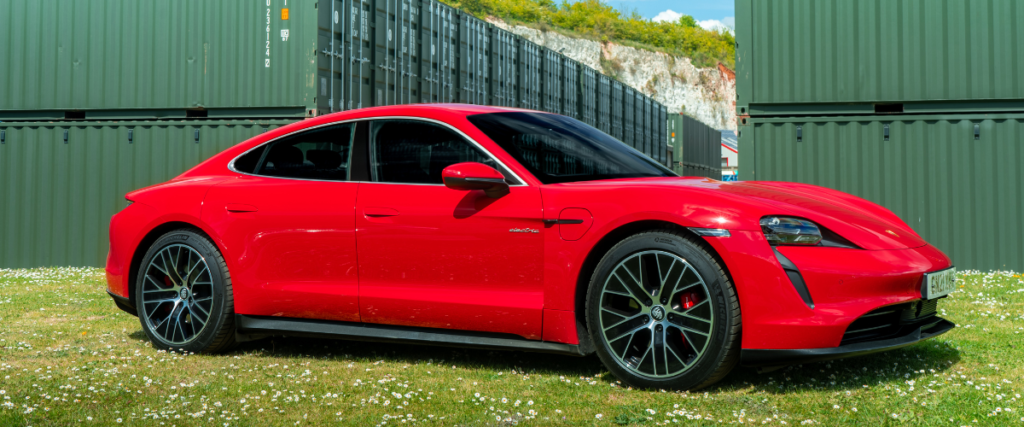 Red Porsche Taycan on grass facing right