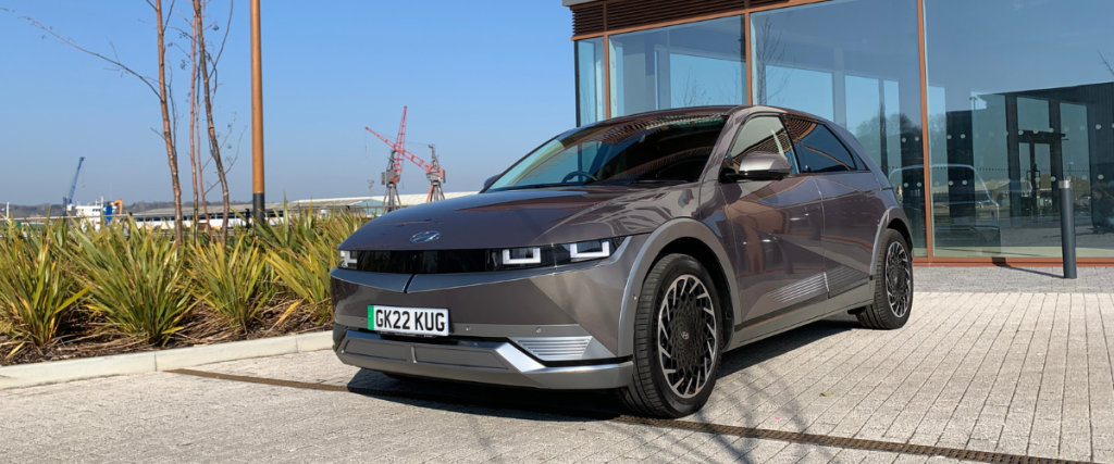 Ioniq 5 in front of glass fronted building.